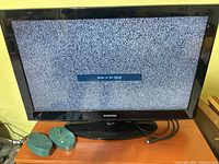 Samsung TV on cabinet showing static screen