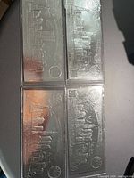 Four silver-plated novelty bills in sleeves laid flat