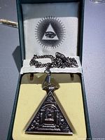 Pendant watch with chain inside presentation box showing All-Seeing Eye graphic