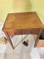 Top and front view of Singer wooden sewing machine cabinet with foot pedal visible underneath