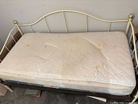Ivory metal daybed frame with stained twin mattress on top