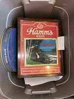 Bin containing wood-framed Hamm's Beer sign ⁄ clock, blue oval metal tray, papers
