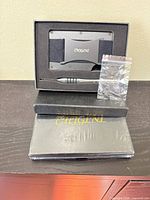 Opened CHGJNL wallet set showing wallet mounted in foam, screwdriver, sealed spare screws, second wallet box below