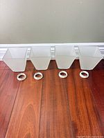 Four frosted glass square light shades lined up with retaining rings in front