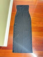 Full view of strapless black maxi dress laid flat