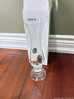 Full view of clear glass bud vase standing beside original box