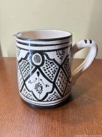 Front view of cream ceramic pitcher with black hand-painted geometric pattern