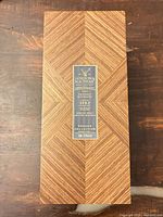 Closed box showing patterned wood veneer and front label