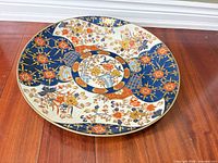 Full view of Imari-style porcelain charger on wood floor