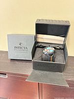 Watch seated in open Invicta Reserve box showing dial and strap