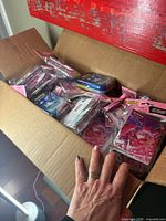 Open shipping box filled with sealed Pokémon TCG mini portfolio packs and a mini tin