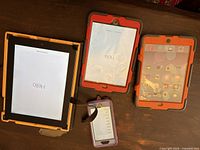 Front view of iPad, iPad mini, spare mini case and iPhone 6s showing powered-on screens