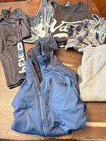 All six garments laid out: jacket, sweatpants, four tank tops