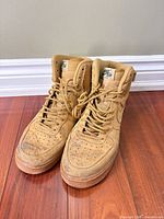Front/top view of both sneakers showing wheat suede uppers, laces, and general wear