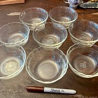 Eight clear Pyrex bowls showing both rim styles with Sharpie for scale