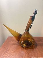 Full view of amber glass porrón showing shape and stopper