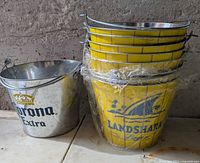 Stacked Landshark buckets wrapped in plastic next to single Corona bucket