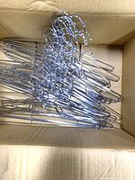 Box containing stacked silver metal hangers