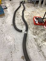 Two long corrugated black hoses laid out showing full lengths