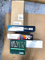 Stacked view of five boxed motorcycle air filters showing brands Hiflofiltro, K&N and part numbers