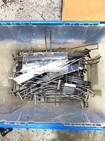 Plastic tote filled with assorted chrome slatwall hooks and clear acrylic shelves