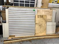 Group of white slatwall, pegboard, plywood sheets and lumber