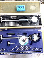 Open yellow and blue cases showing analog and digital bore gauges with accessories and blue anvil block