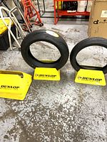 Two Dunlop yellow tire stands shown holding motorcycle tires, additional stands visible