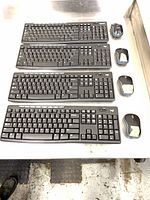 Three of the four keyboard, mouse and receiver sets laid out on table