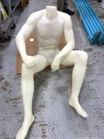 Fully assembled headless male mannequin seated on floor