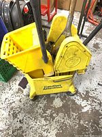 Yellow mop bucket with wringers and mop handle visible