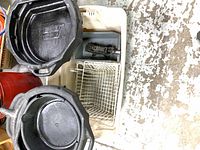 overhead view of two oil drain pans, jack, and stacked pegboard baskets