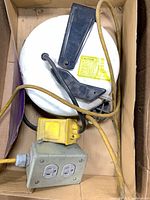 Entire reel with attached cord and outlet box visible in carton