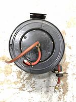 Top view of black steel hose reel with red hose and fittings visible