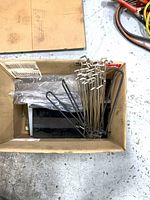 Box containing pegboard hooks and some black metal shelves