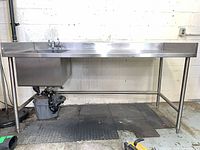 Front view of entire stainless sink workstation showing basin, faucet/eye wash and legs