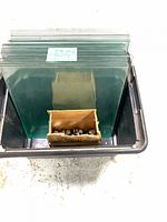 Stack of tempered glass panels and box of hardware in bin