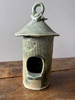 Front view of ceramic birdhouse showing entrance, roof, hanging loop