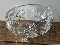 Side view of clear cut crystal bowl on three feet showing starburst pattern