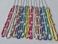 Front view of 11 beaded daisy chain necklaces laid flat