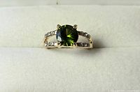 Ring front view showing green stone and side clear stones