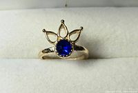 Front view of gold-tone ring showing blue stone and lotus crown design
