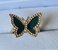 Front view of gold-tone butterfly ring with green enamel wings