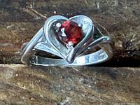 Full view of sterling silver ring with heart-shaped setting and red gemstone