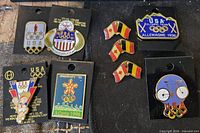 All nine Olympic-themed enamel lapel pins arranged on surface showing fronts and backing cards