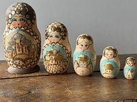 Full set of five stacking dolls on wooden surface