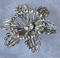 front view of silver-tone rhinestone floral wreath brooch pin on white background