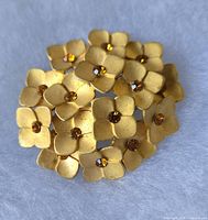 Front view of gold-tone floral brooch with amber rhinestones