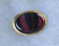 Front view of oval brooch showing cabochon colours and gold-tone frame