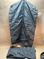 Three blue garment bags, one hanging open, two folded